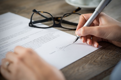 Personne qui signe sur une feuille en papier