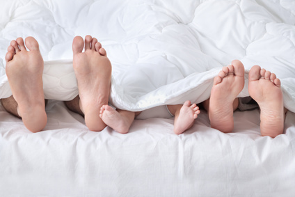 3 paires de pied dépassant d'une couette