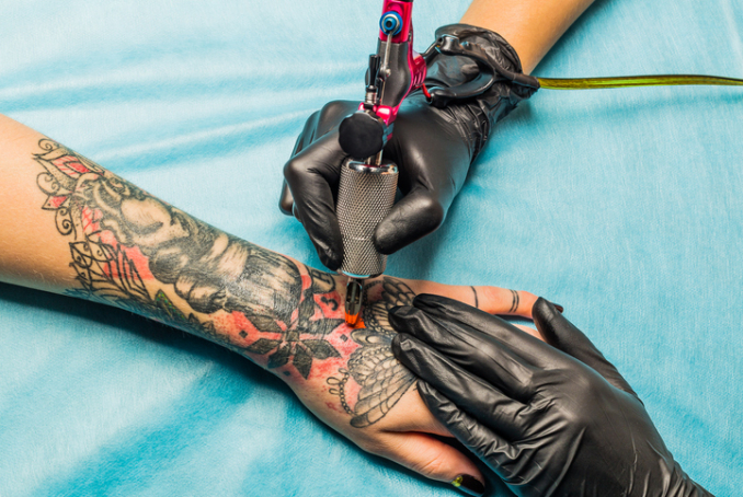 Professionnels du tatouage tatouant sur un bras 