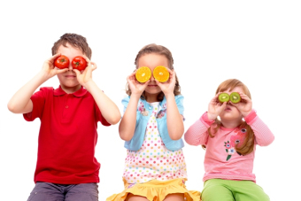 3 enfants qui cachent leurs yeux avec des rondelles de fruits